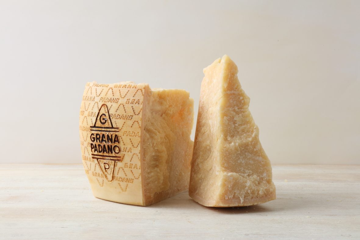 Meule de Grana Padano AOP entière avec sa croûte jaune foncé et une part découpée