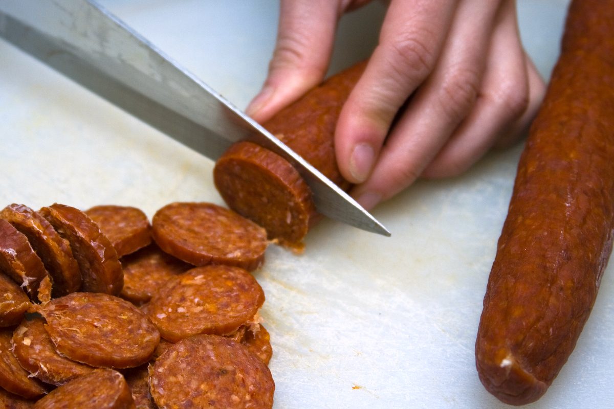 Tranches de pepperoni rouges et piquantes disposées sur une planche en bois