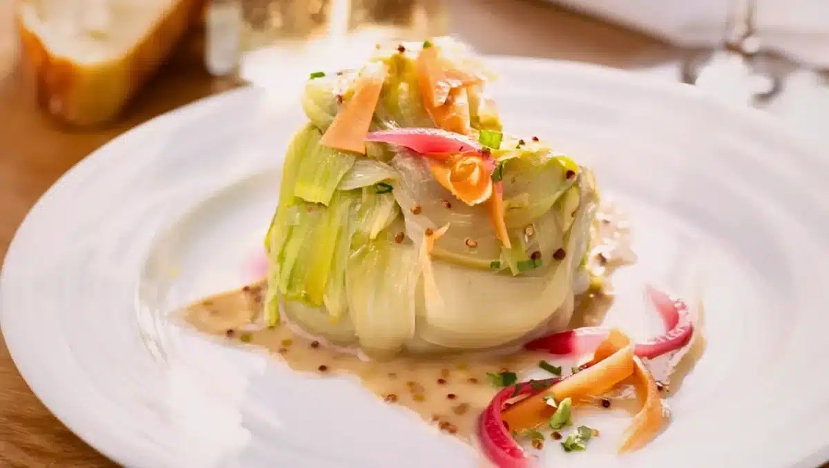 Fondue de poireaux crémeuse servie dans une assiette avec des herbes fraîches
